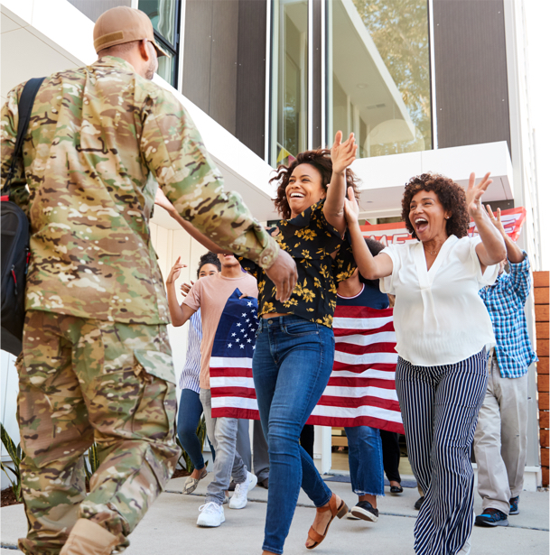 A member of the military reuniting with family who holds up an American flag at an airport.