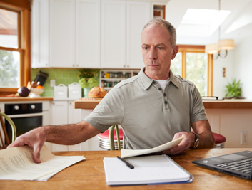 A man examining papers at his kitchen table