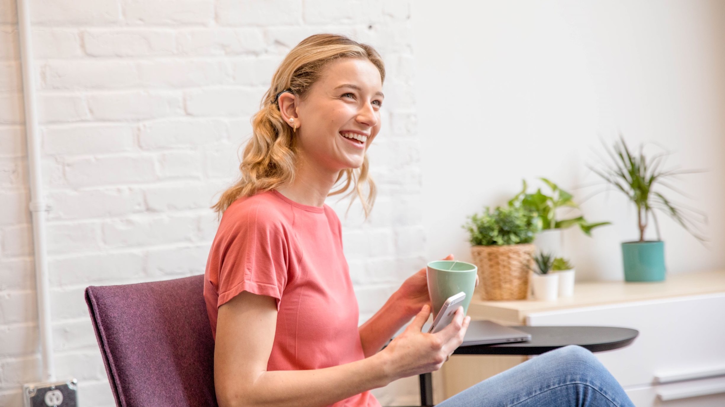 Young female student sitting in a casual relaxed environment with a notepad looking up and smiling.