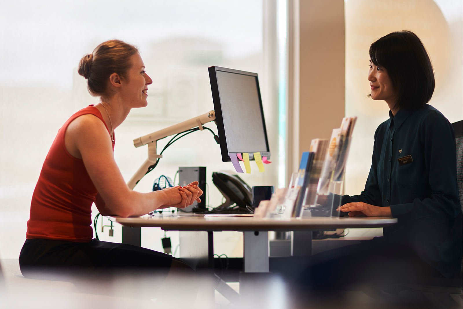 Two female employees chatting over desk