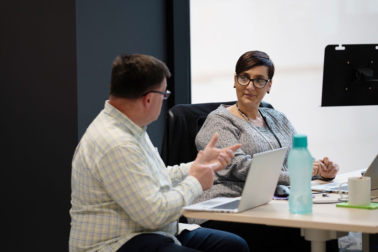 Male and female IAG employees chatting in the office