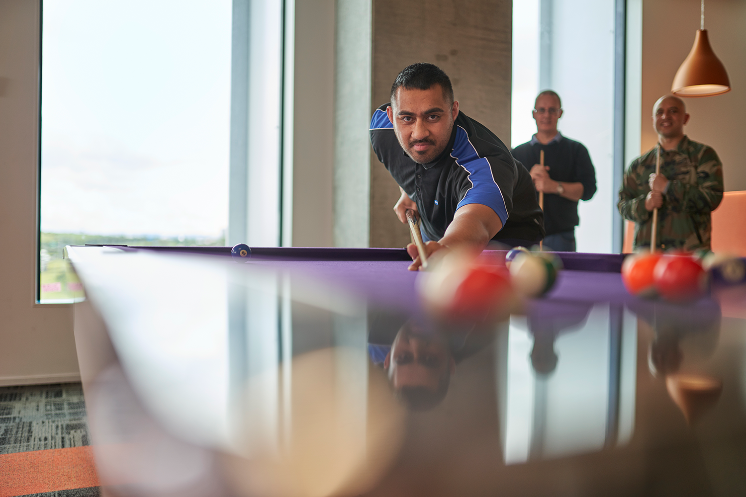 Three IAG employees playing pool in the office