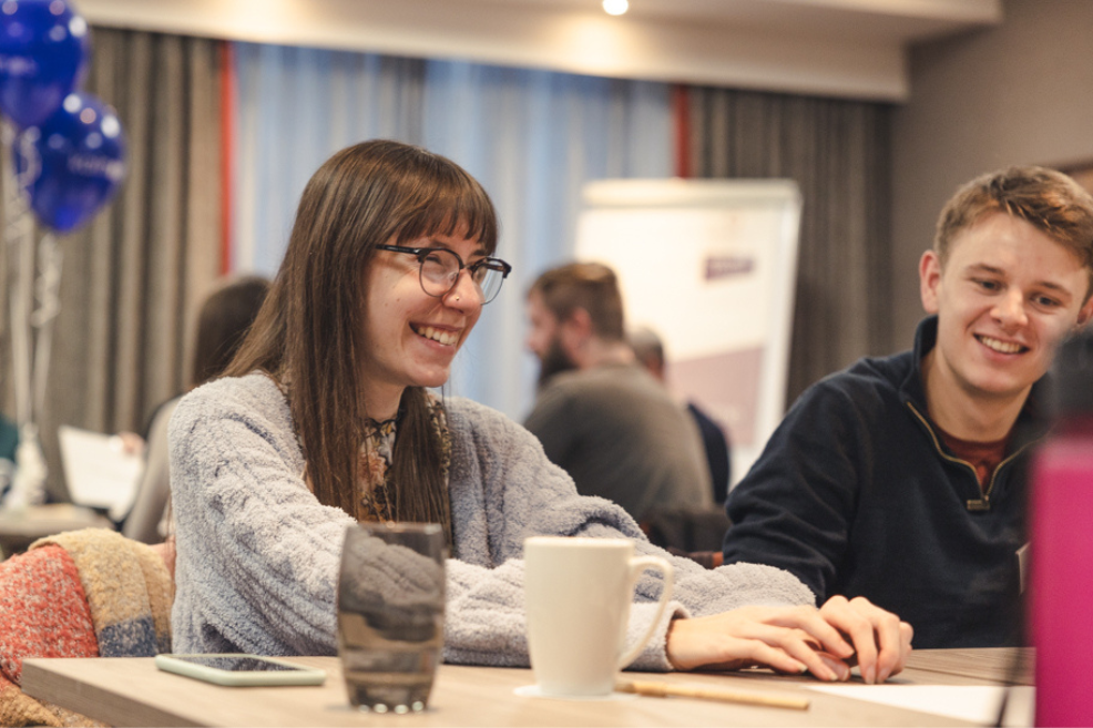 Two colleagues sitting at a table chatting and laughing