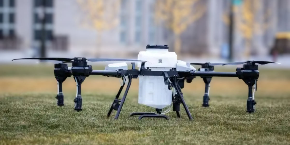 Large industrial drone with mounted payload resting on grass, used by DMR Technologies for professional aerial operations.