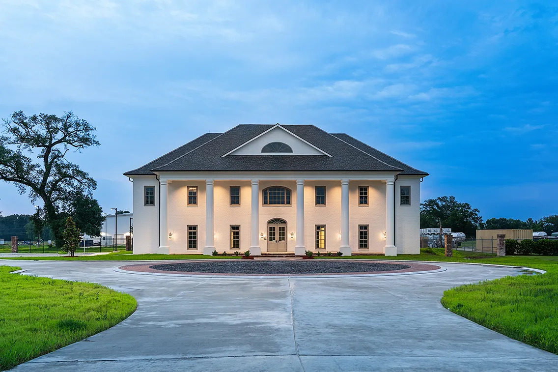Front view of the Skyfall Biologicals headquarters building at dusk with columned façade and landscaped circular drive.