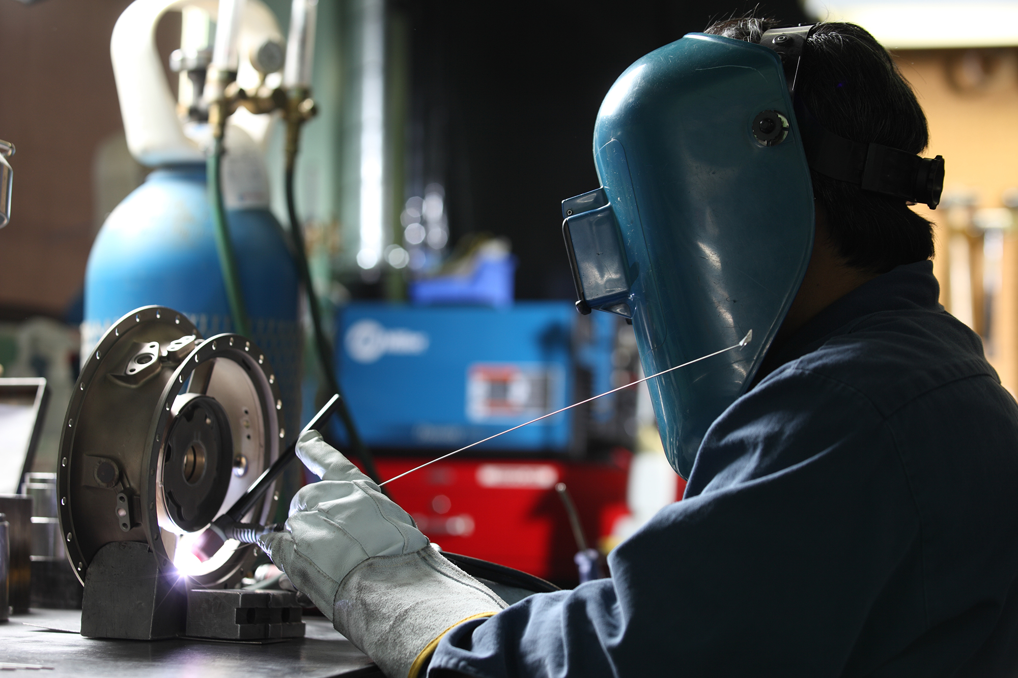 Cadorath technician wearing a welding helmet and gloves performing precision welding on a critical metal component in a Louisiana manufacturing shop.