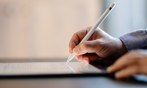 Hand holding a pen, writing on tablet