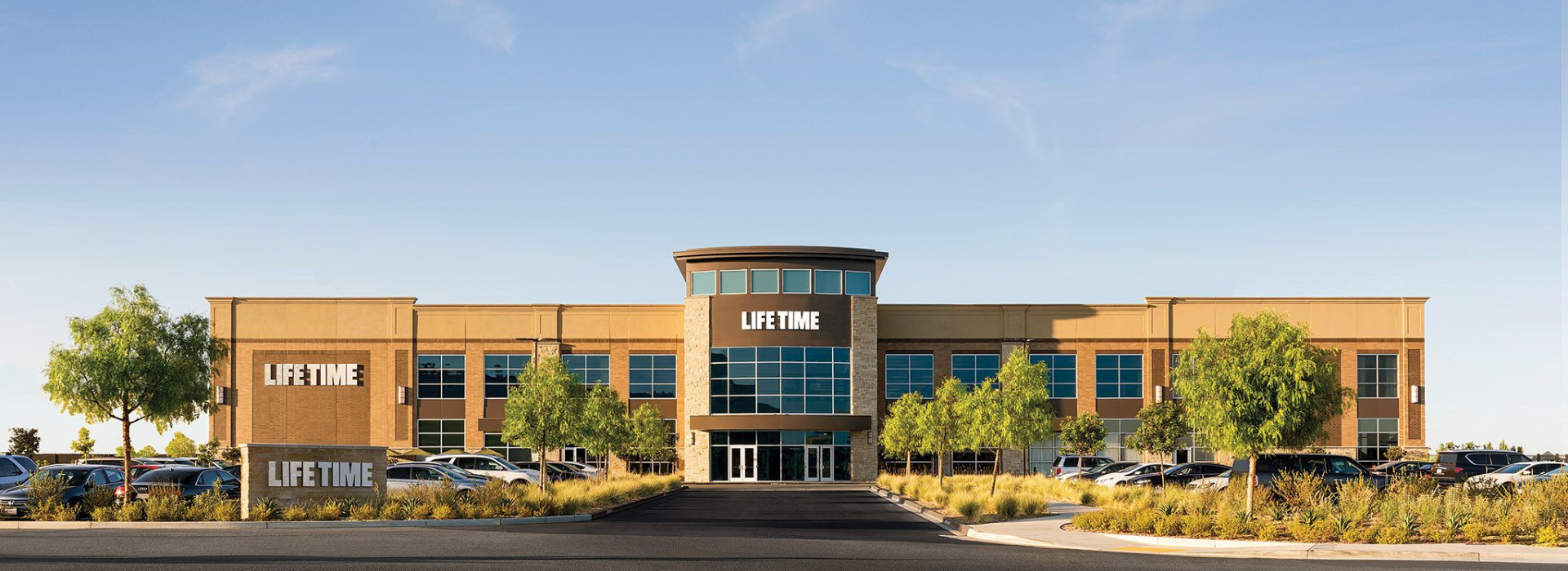 Outdoor front view of Life Time Las Colinas entrance with clear blue skies.  