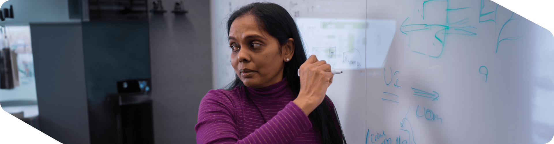 Tech associate writing on a whiteboard in a meeting