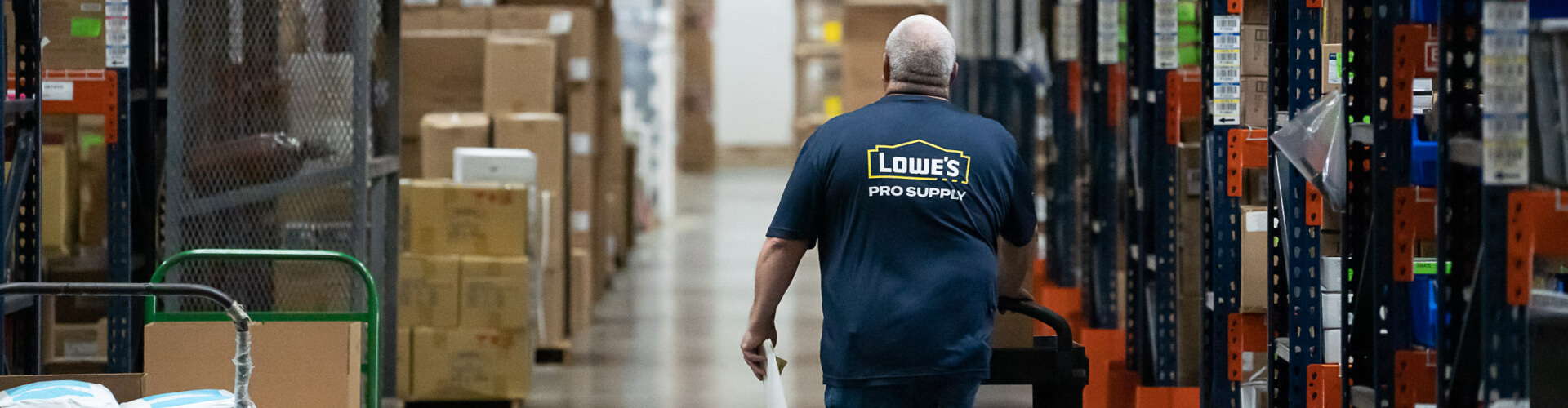 Lowe's Pro Supply warehouse associate pushing a cart