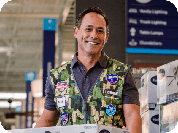 Lowe's associate stocking fans while wearing a military vest