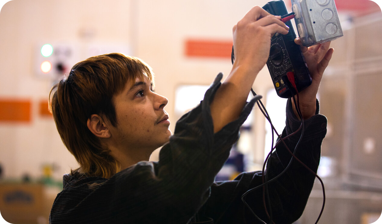 Male skilled trades student testing an electrical outlet
