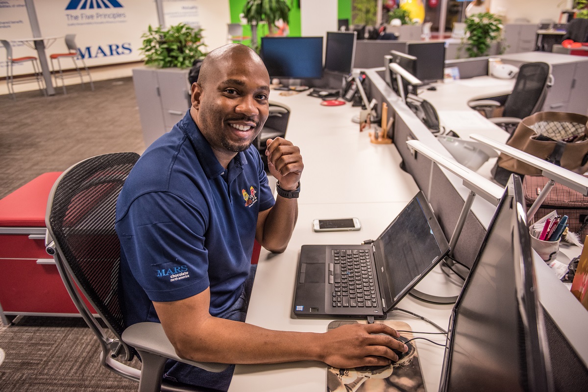 A image of a Mars Associate seated at his desk smiling