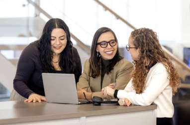 Three Mastercard employees sitting around shared computer