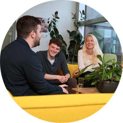 Three employees sitting on yellow couches