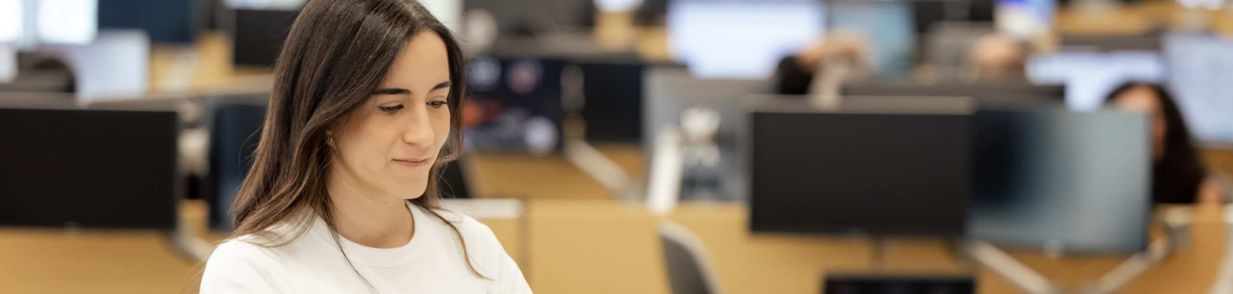 Woman sitting at desk with desks behind her