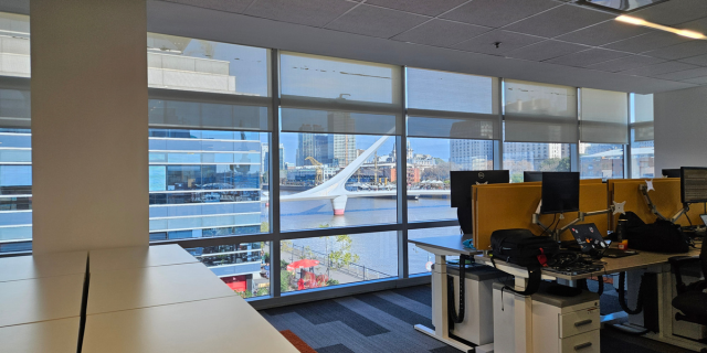 Photo of Mastercard Buenos Aires office space featuring desks and screens, with wall-to-ceiling windows offering views of the city.