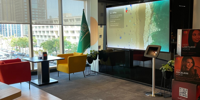 Space in Mastercard Riyadh office with large screen, tables, chairs, and floor to ceiling windows