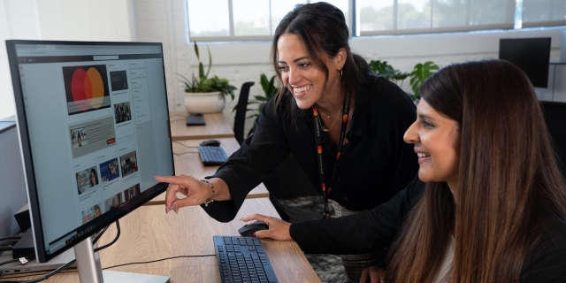 Photo of Mastercard colleagues smiling while looking at a computer screen.