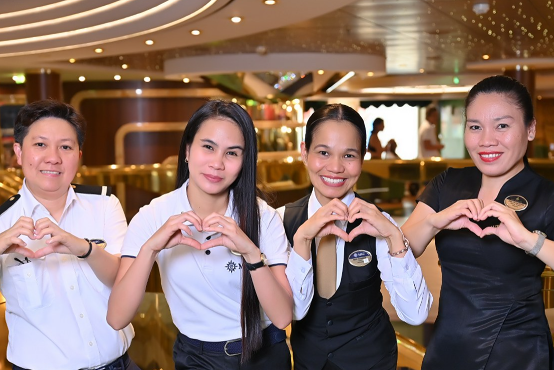 MSC Cruises crew members forming a heart with their hands, symbolizing unity and team spirit onboard.