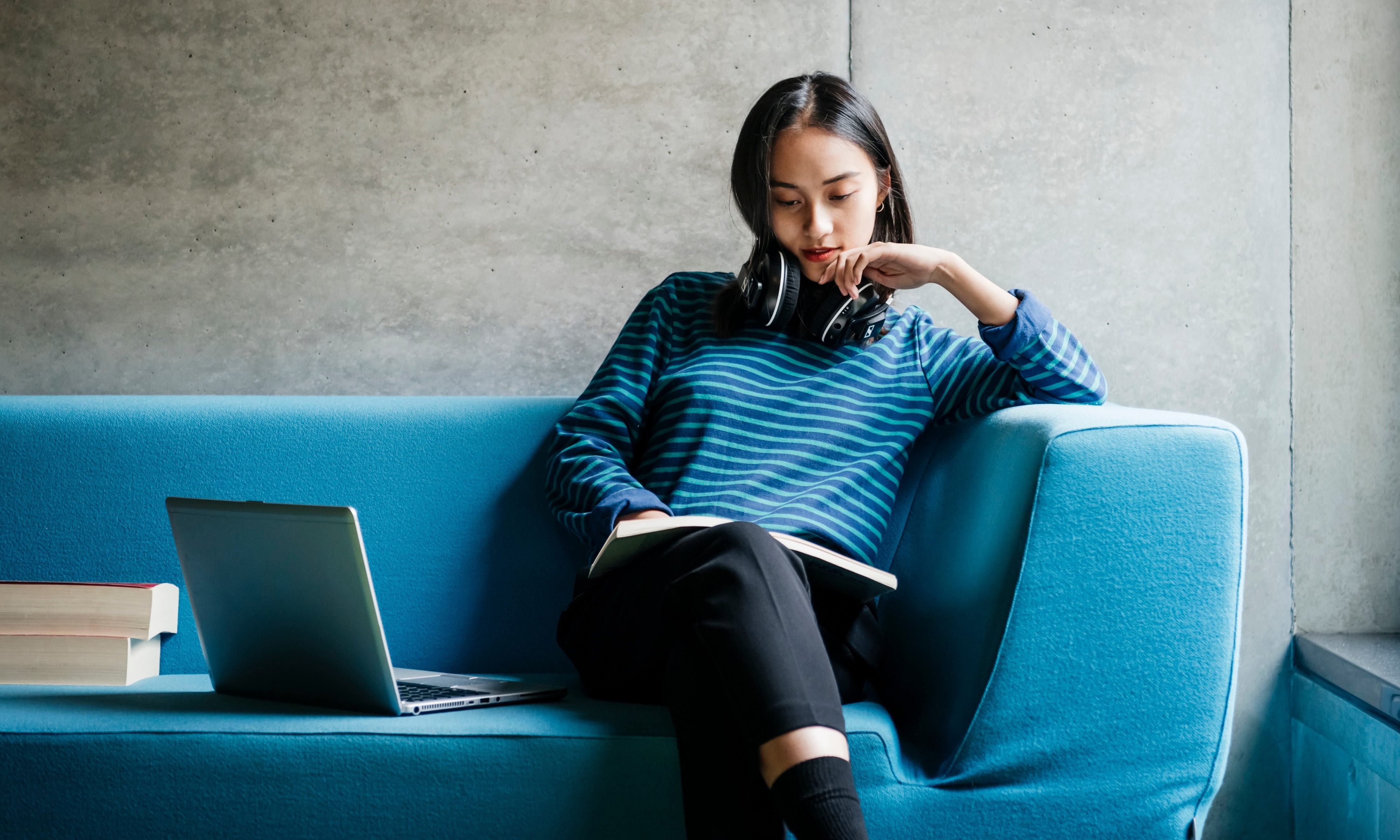 A person sitting on a blue couch with a computer