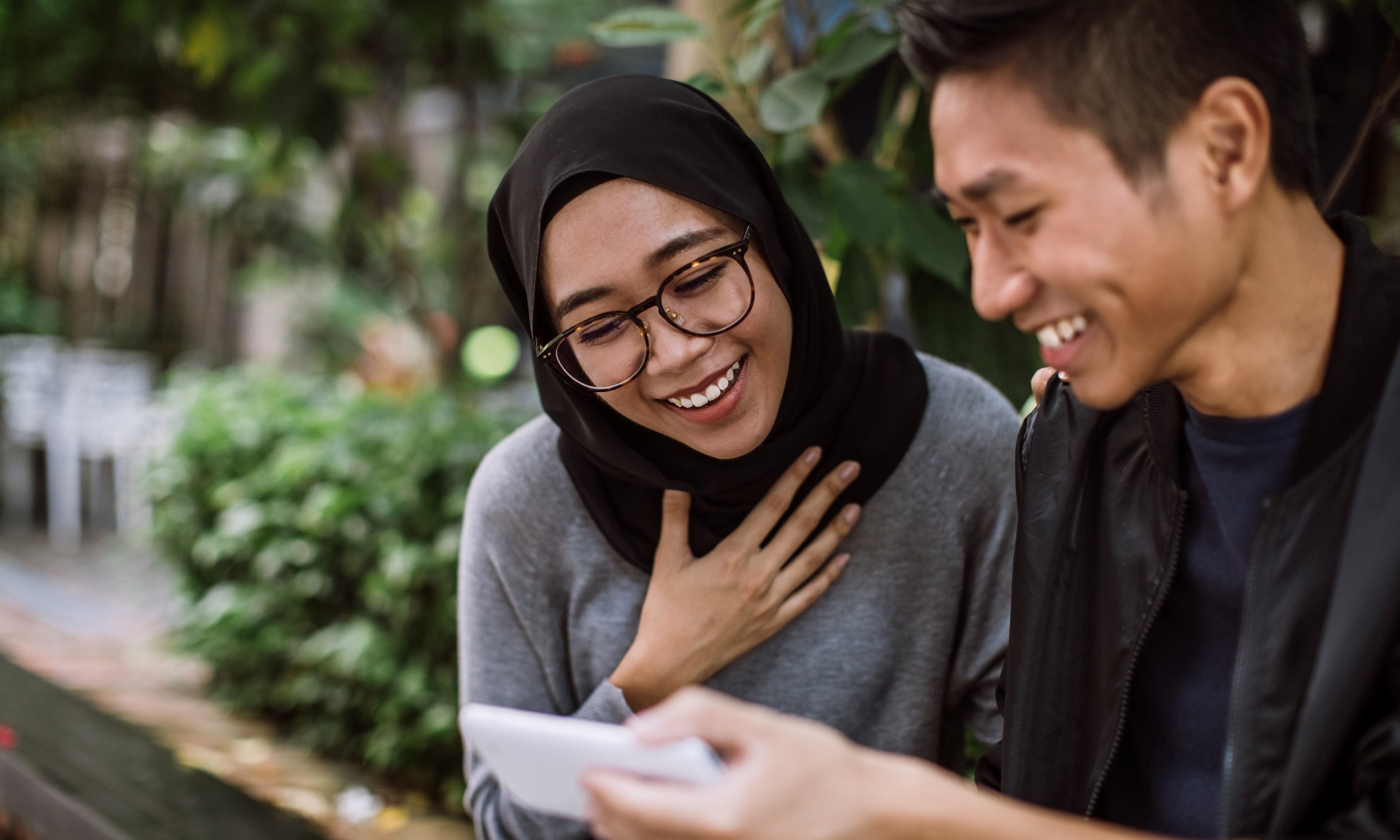 Deux personnes regardent un téléphone en souriant 