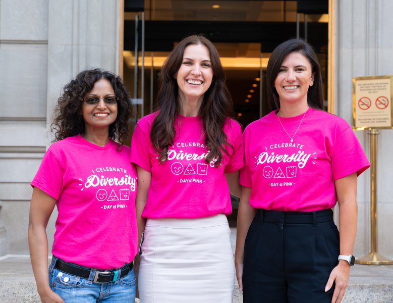 A group of people in pink shirts standing out front of building