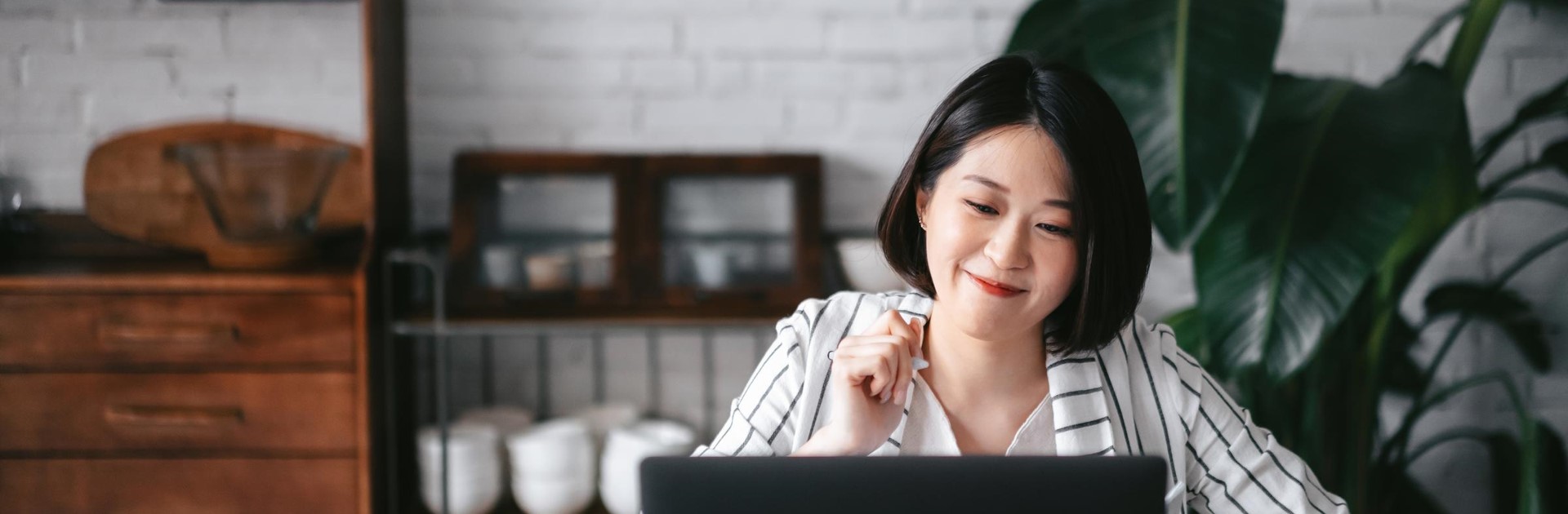 Une femme regarde un ordinateur portable en souriant 