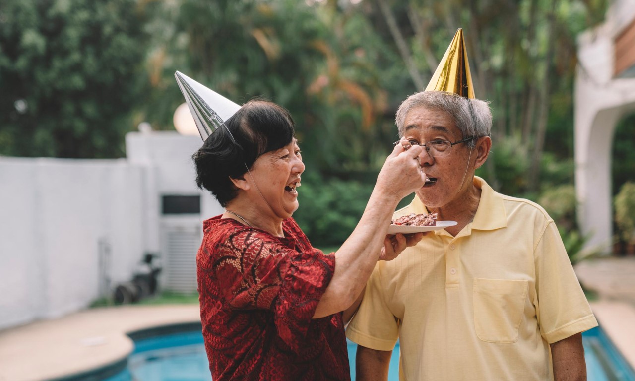 Two people eating cake with party hats