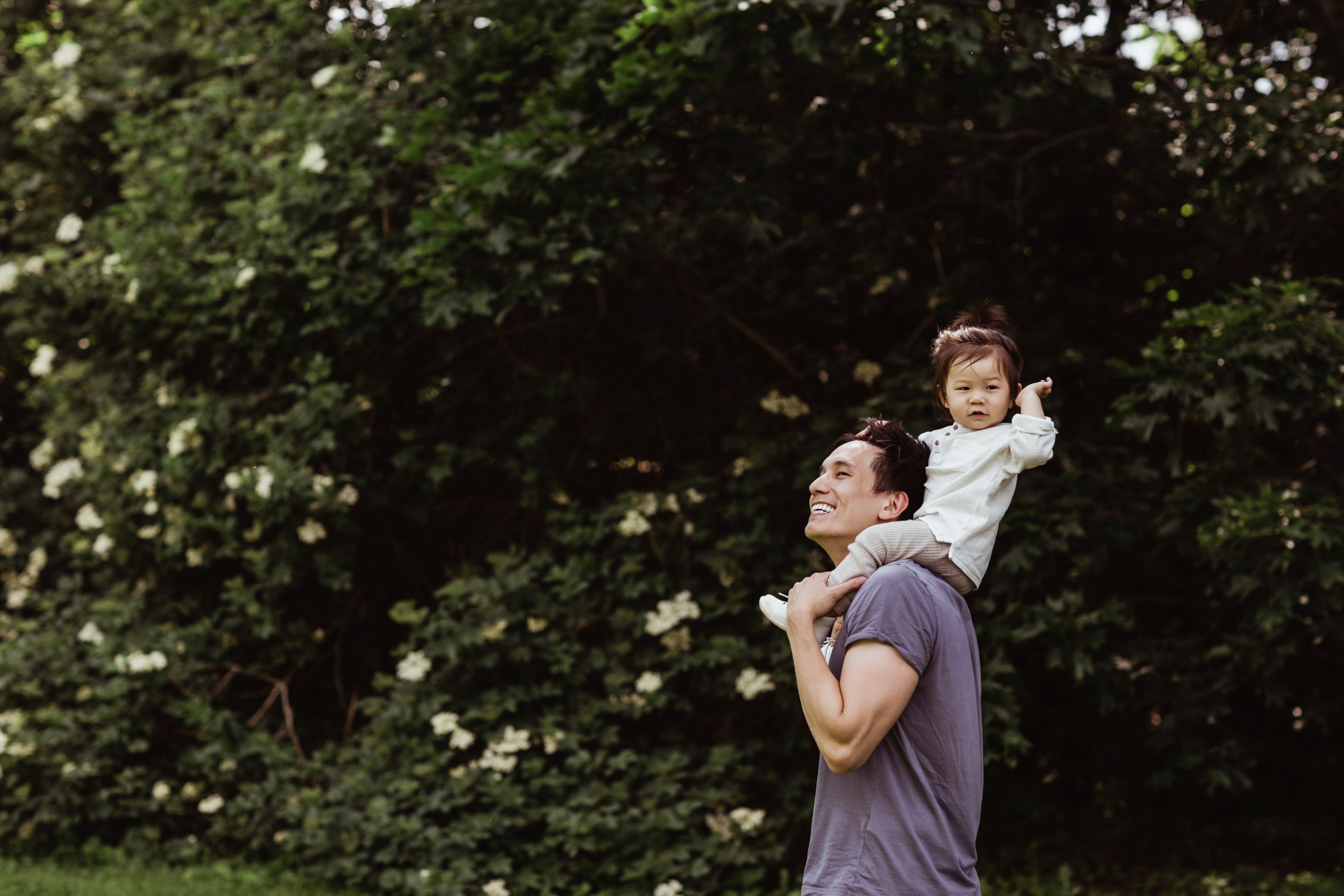 Man with child on shoulders smiling looking into distance