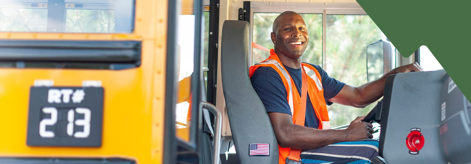 A school bus driver smiling sitting behind the wheel of a Summit School Services School Bus,, showcasing pride in her work.