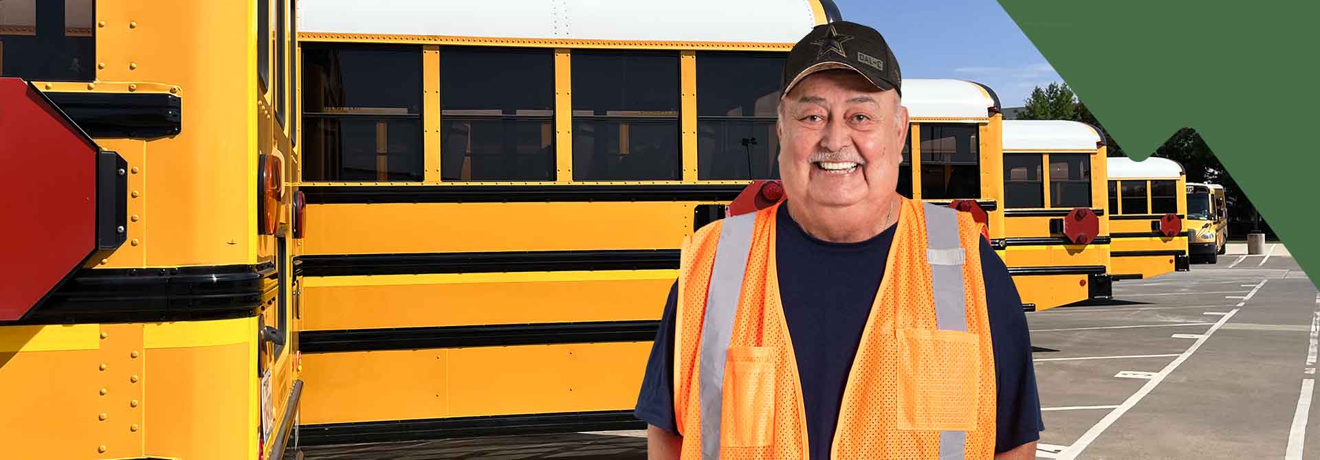 A female school bus driver smiling and standing confidently in front of a row of parked school buses, showcasing pride in her work.