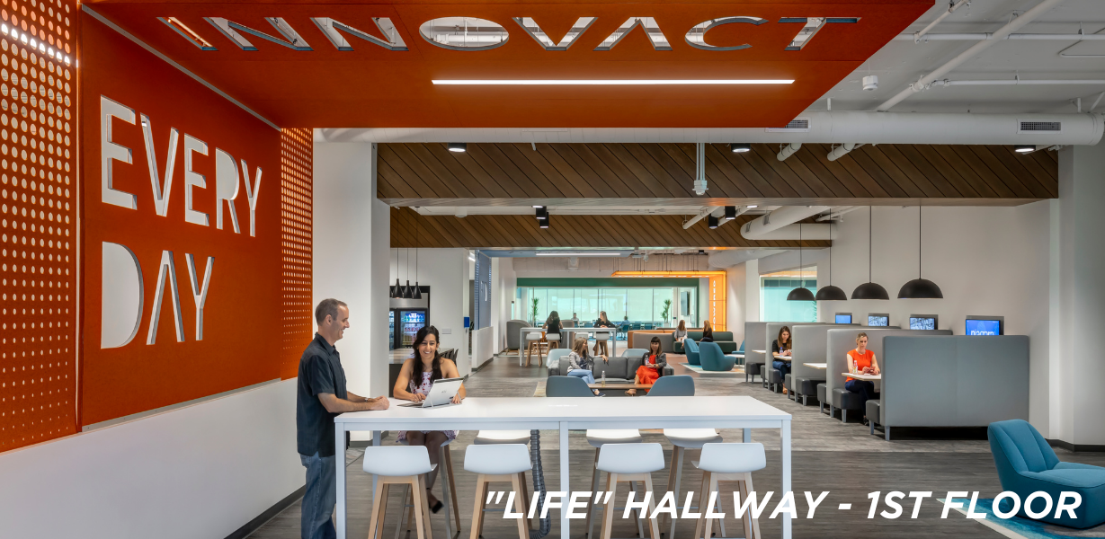The "LIFE" hallway; long room with high-top tables and chairs and booths with pendant lamps 