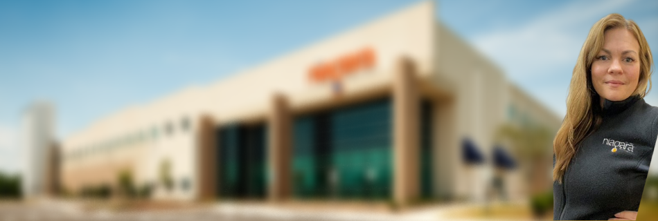 Woman soft-smiling in front of a blurred-out Niagara building 