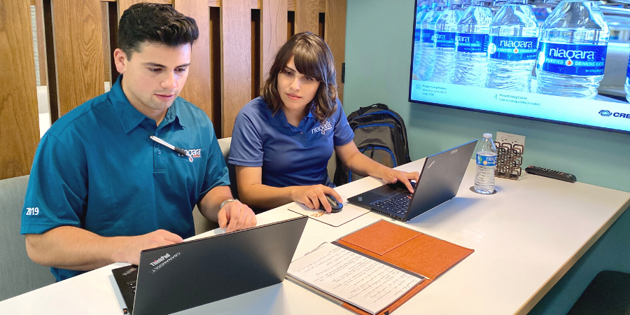 A man and a woman working on their computers in an office room.
