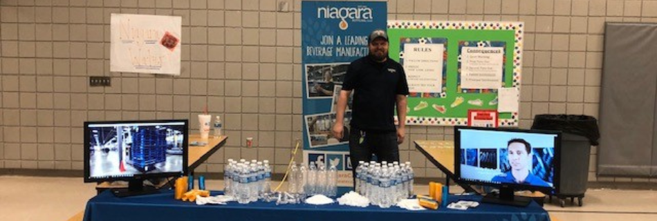 Man smiling behind a Niagara job fair table 