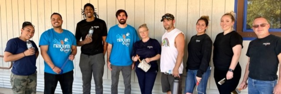 Niagara team members smiling in front of an elementary school