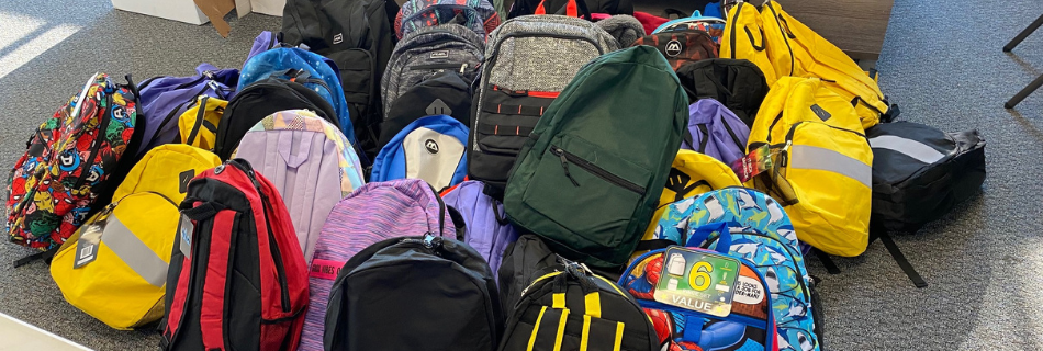 Backpacks laid out on the ground of a parking lot 