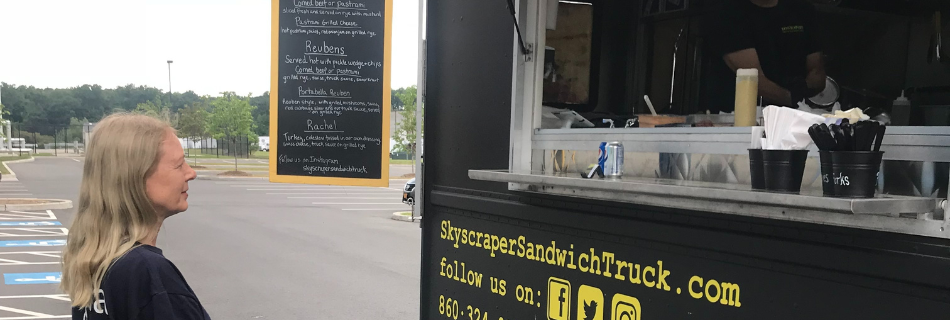 Photo of blonde woman waiting for food at a sandwich food truck 