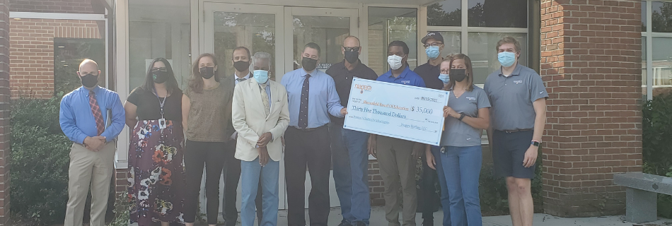 Photo of Niagara team members holding up a check in front of an elementary school 
