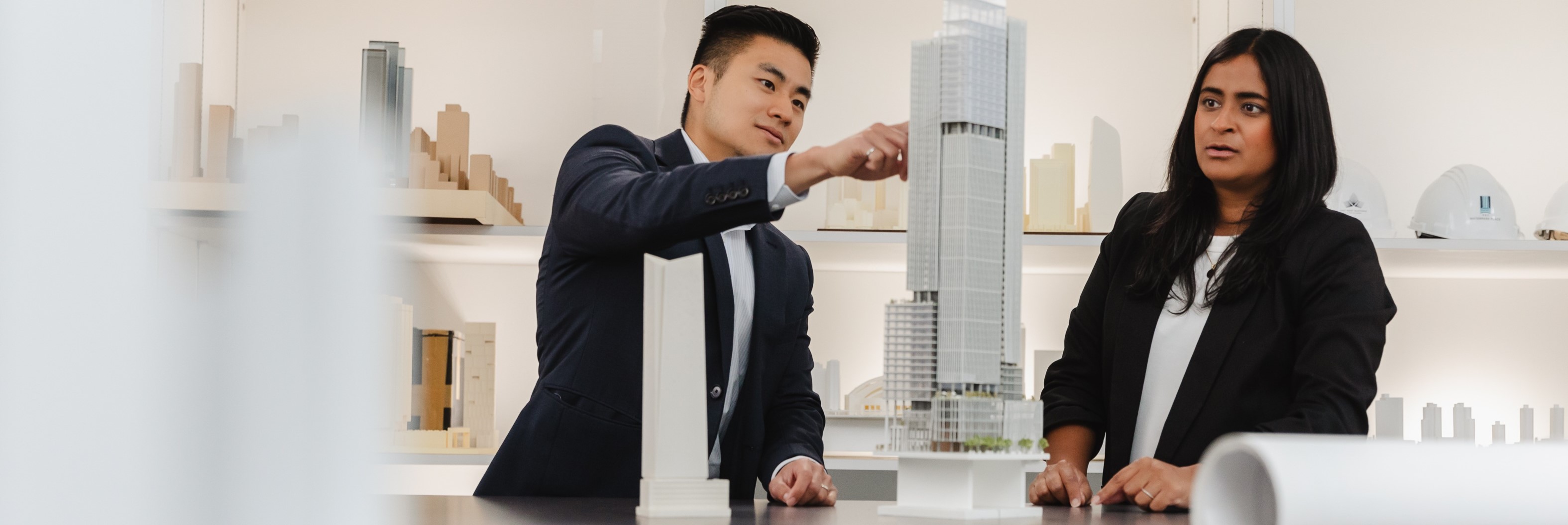 A woman and man looking at a model of a skyscraper