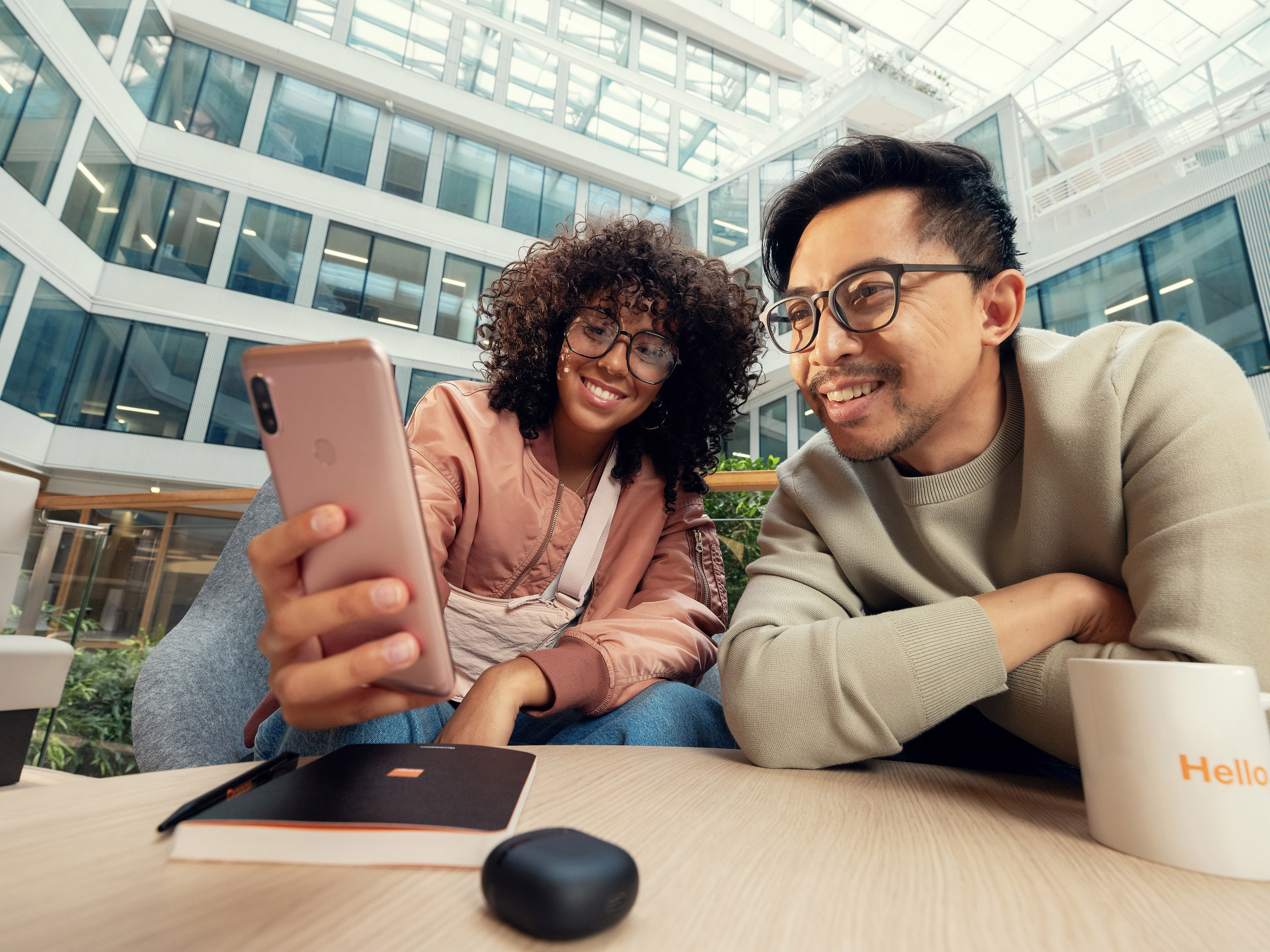 An Orange employee and a colleague are laughing together in the office break area.