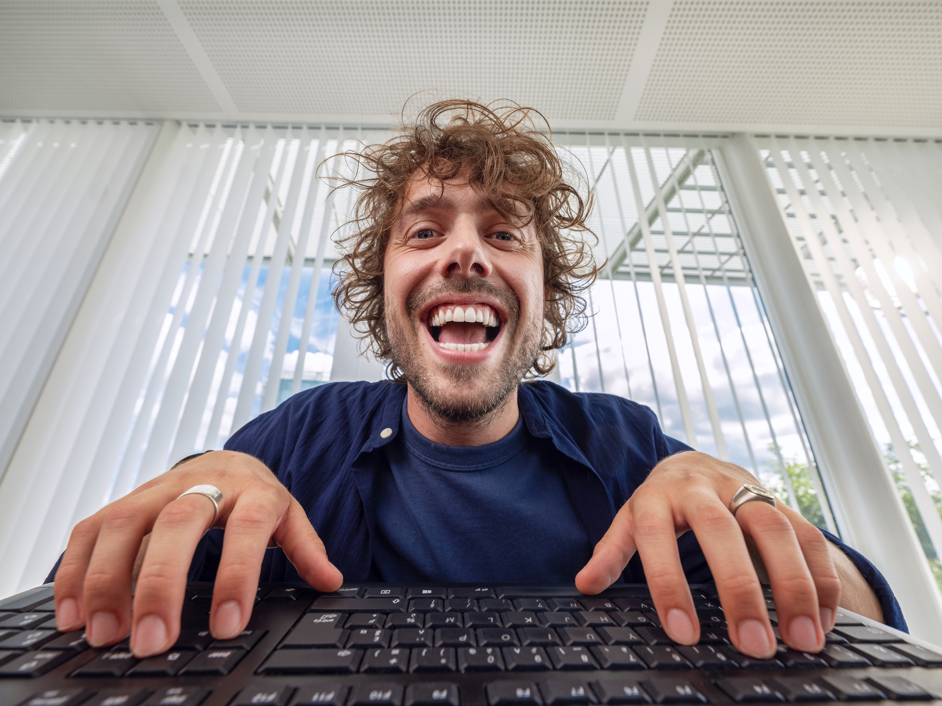 A young Orange employee laughing in front of his computer