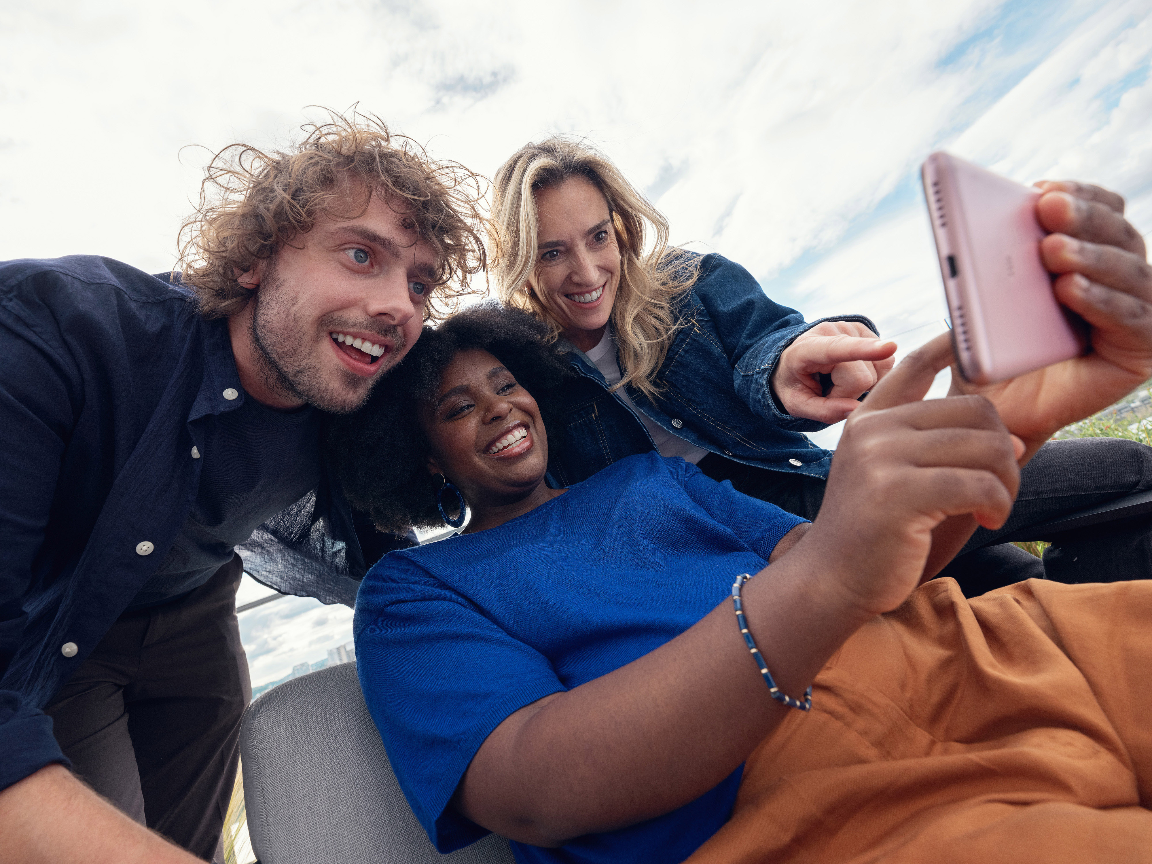 Orange employees sharing a moment around a smartphone screen.