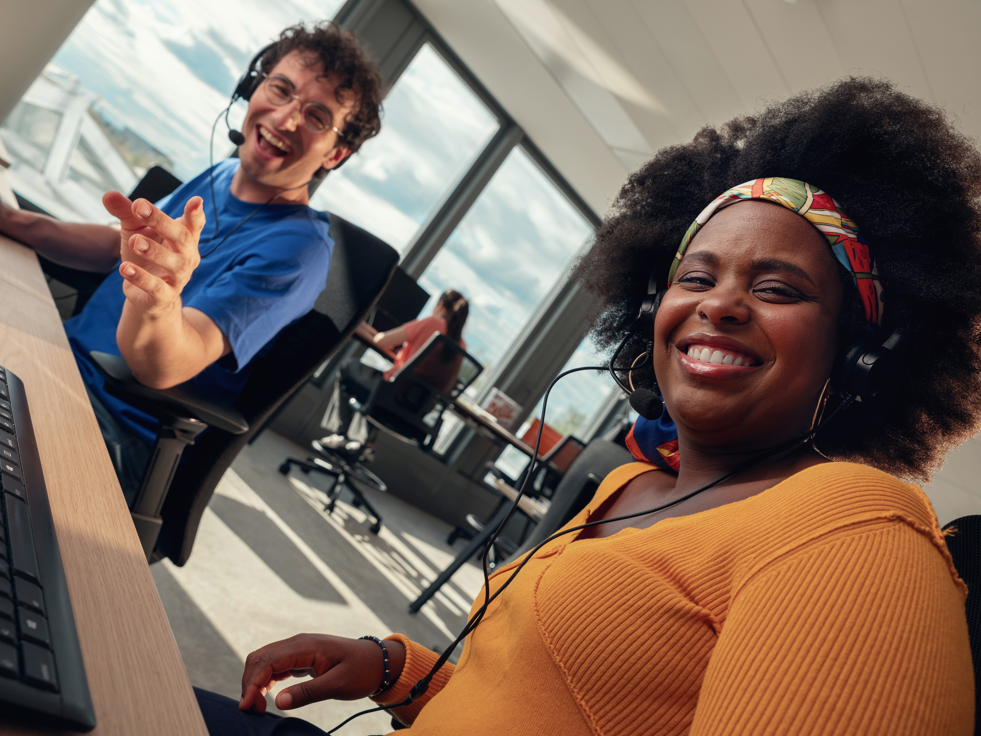 Two colleagues smiling at their desks