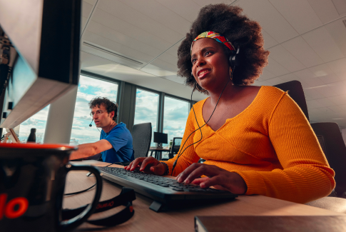 An Orange employee working on her computer with a headset
