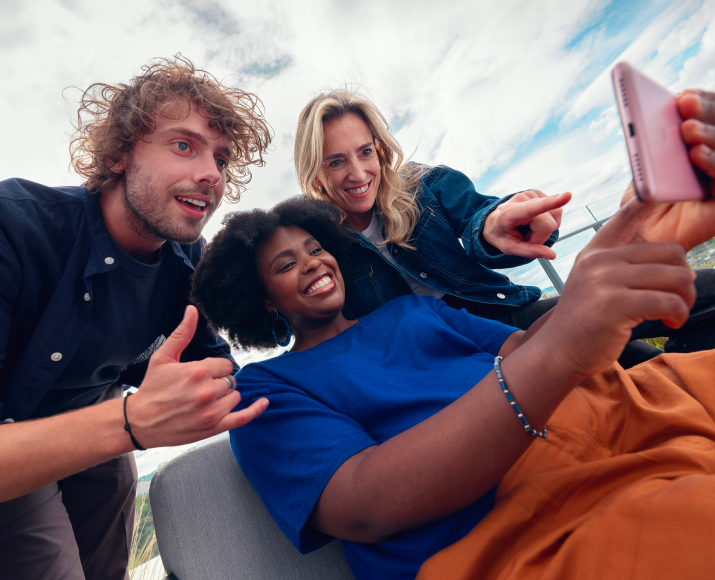 Several Orange colleagues looking at a video on a phone.