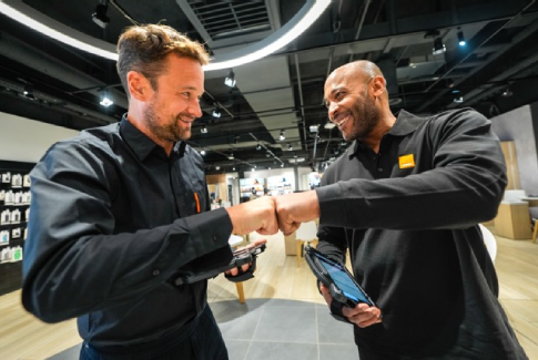 Two Orange employees greeting in a store