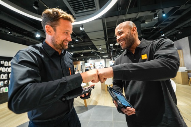 Two Orange employees greeting in a store