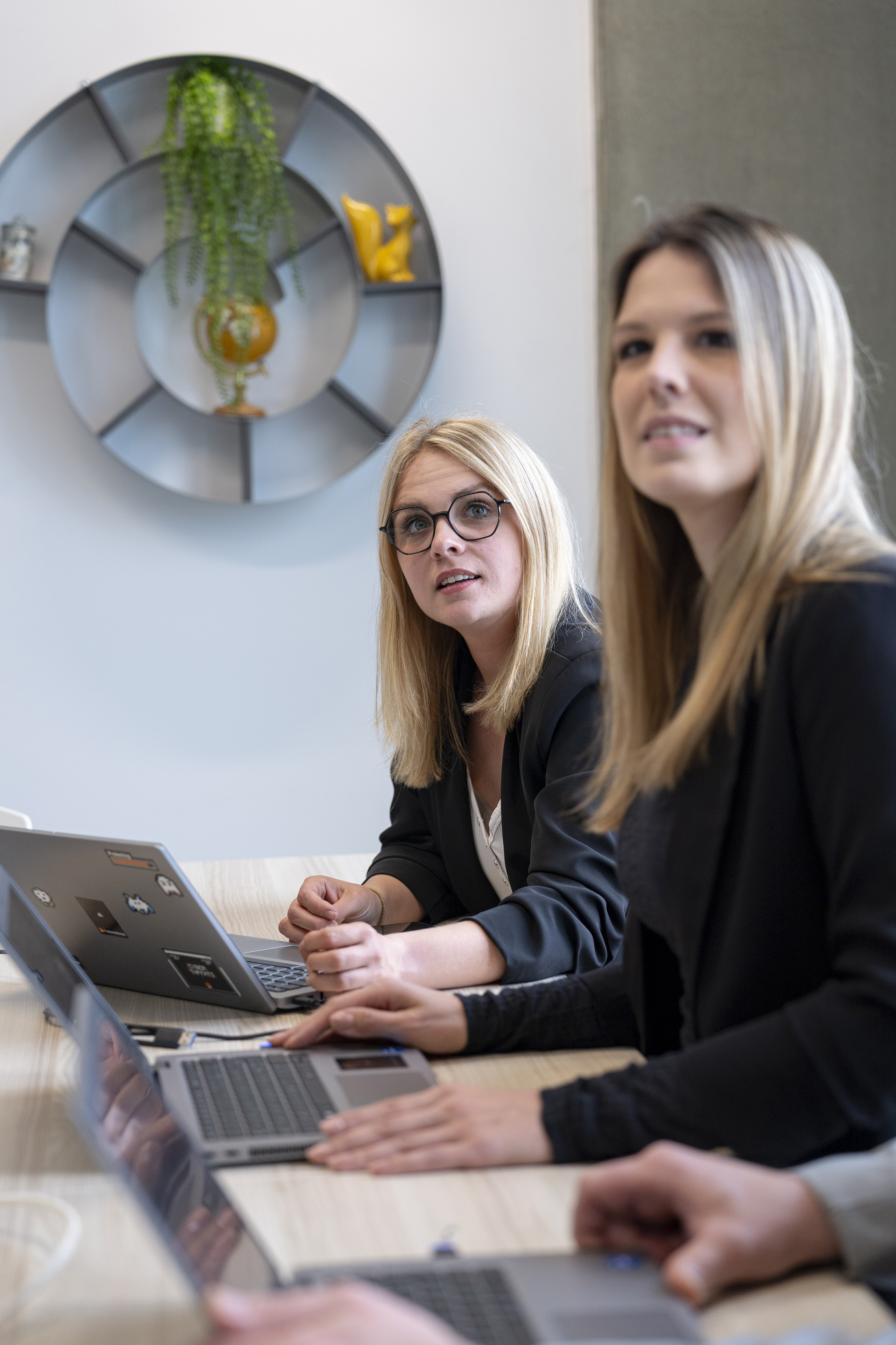 Orange female employees in a meeting around a computer